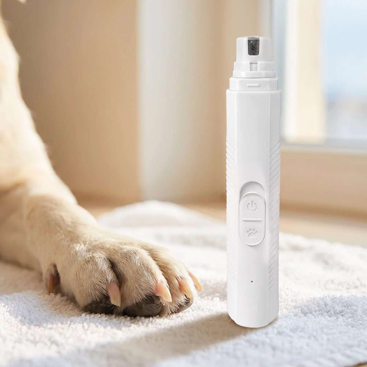 Close-up of a dog's paw resting on a towel beside the white Trimvoro Aegis Pro Nail Grinder