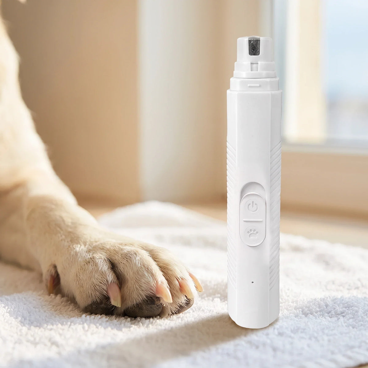 Close-up of a light-coated dog's paw resting on a white towel beside a white Trimvoro nail grinder